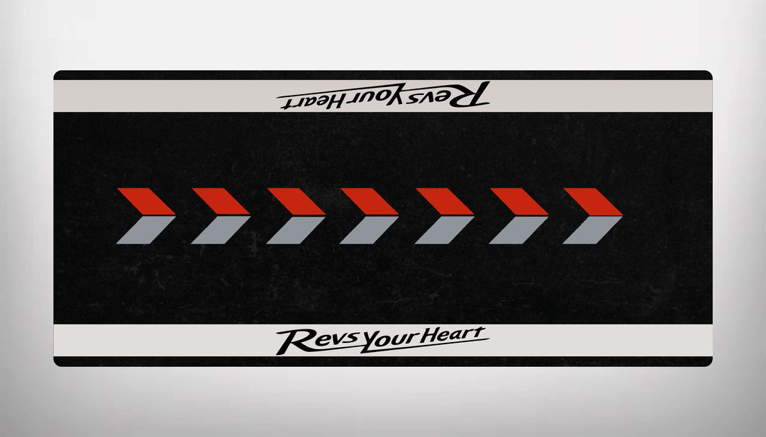 The Motorcycle Pit Mat, a rectangular mat for Yamaha Universal, features red and gray arrows on black with Revs Your Heart in white at the top and bottom.