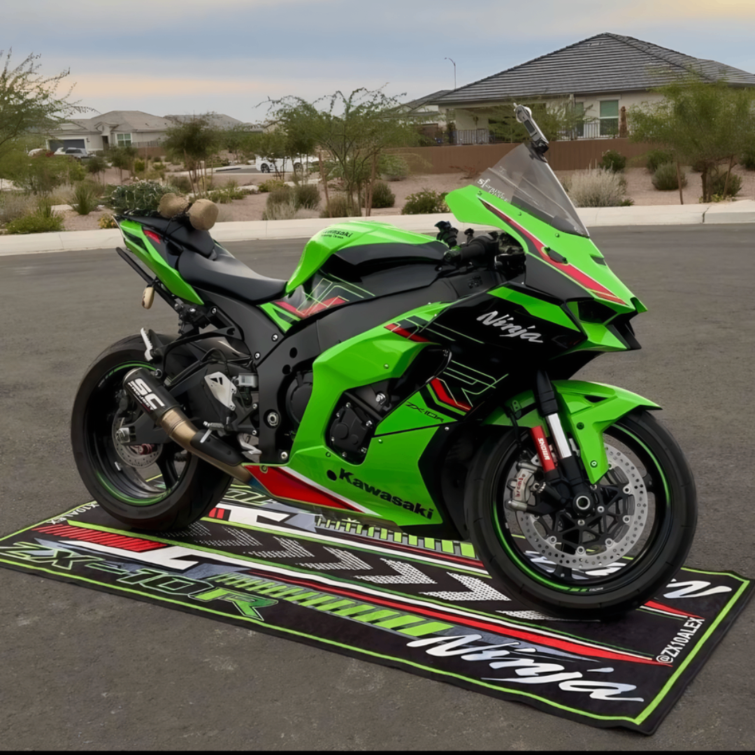 A vibrant green Kawasaki Ninja motorcycle is parked on a motorcycle garage mat in a suburban neighborhood. The bike boasts sporty decals and an aftermarket exhaust. In the background, houses and trees stand beneath a clear sky.