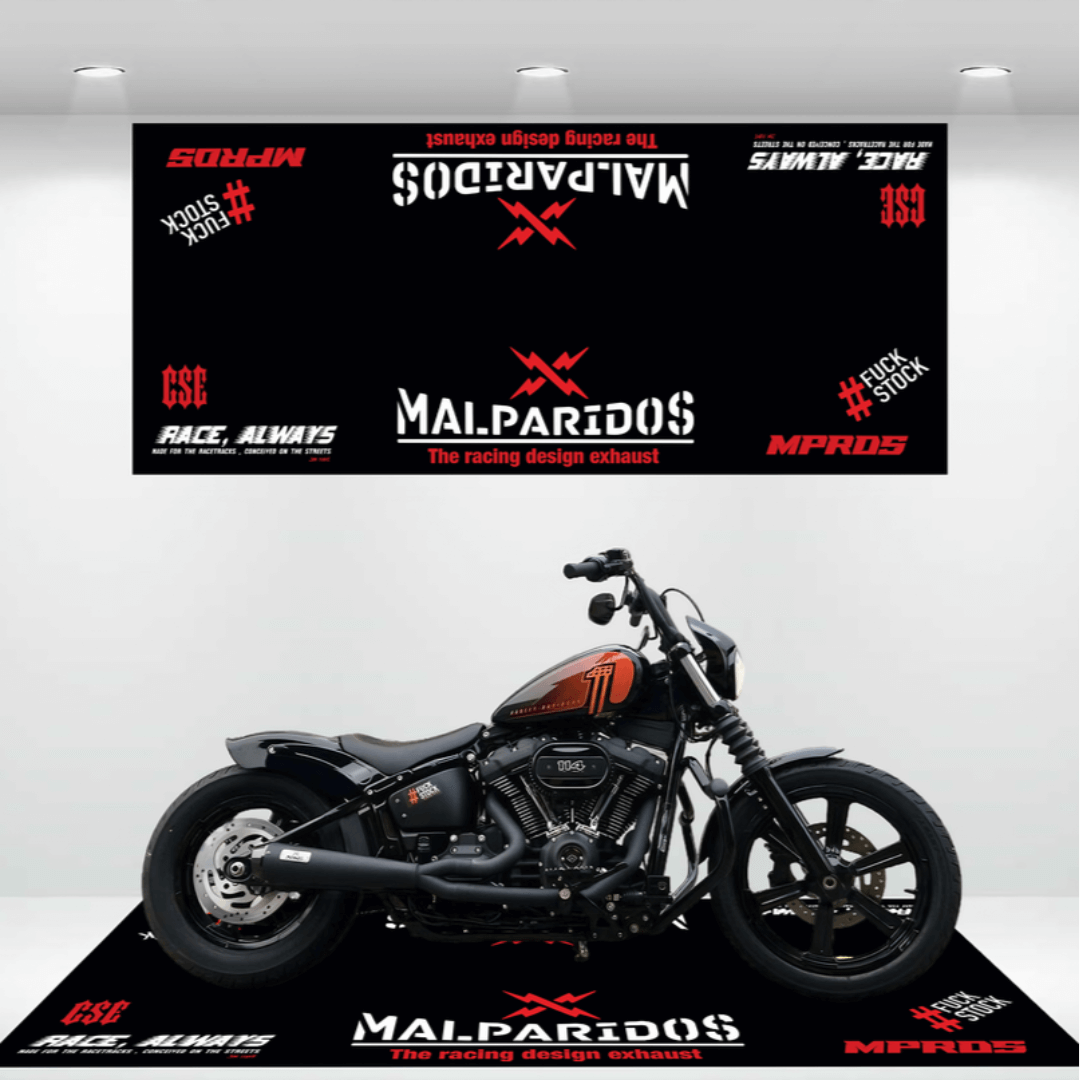 A black motorcycle is displayed on a platform with branded graphics and a sleek motorcycle garage mat. The backdrop reads Malparidos: The Racing Design Exhaust along with various logos and text such as #LockStock and Race, Always.