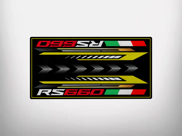 The Motorcycle Pit Mat features the text RS 660 in bold red and white on a black background with green, white, and red flag-like stripes. Yellow arrow-like shapes and a thin yellow border complete this design, ideal for an RS660 motorcycle garage mat.