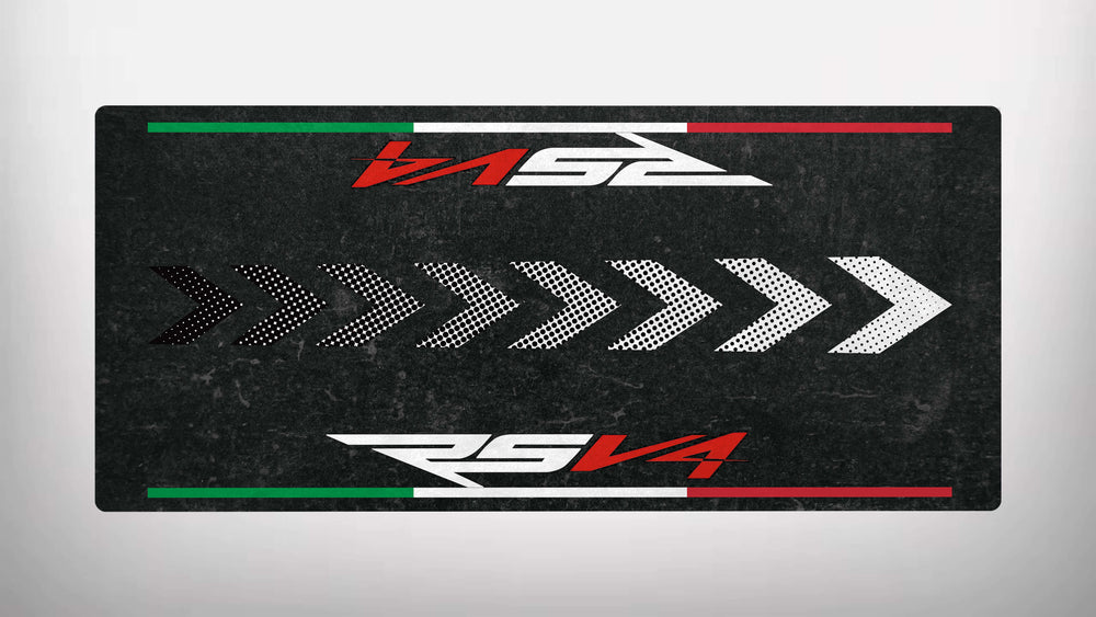 The Motorcycle Pit Mat features a rectangular design with a black background and white right-pointing arrows. It displays RSV4 and RS 52, along with green, white, and red horizontal stripes on the top and bottom edges.