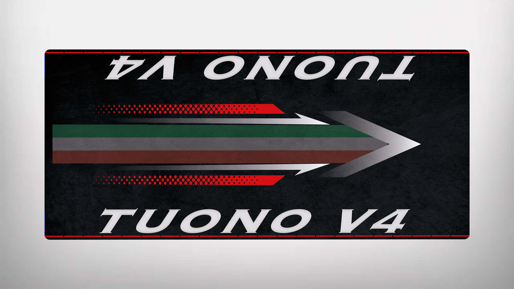 On a sleek, black Motorcycle Pit Mat for the Tuono V4, a stylized arrow with red, green, and gray stripes points right. The words TUONO V4 are boldly written in white at both the top and bottom of this dynamic design.