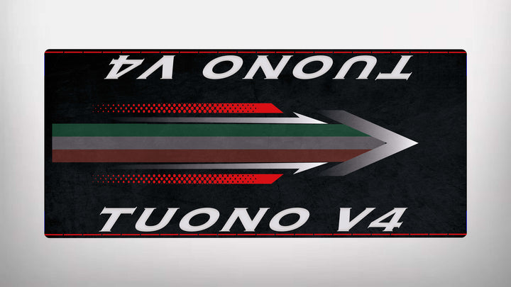 On a sleek, black Motorcycle Pit Mat for the Tuono V4, a stylized arrow with red, green, and gray stripes points right. The words TUONO V4 are boldly written in white at both the top and bottom of this dynamic design.