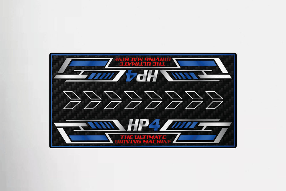 A sleek Motorcycle Mat for HP4 Carbon by Motorcycle Pit Mat mimics a rectangular license plate with a carbon fiber look, blue and silver highlights, bold HP4 text, The Ultimate Driving Machine in red, and horizontal arrows in the design.