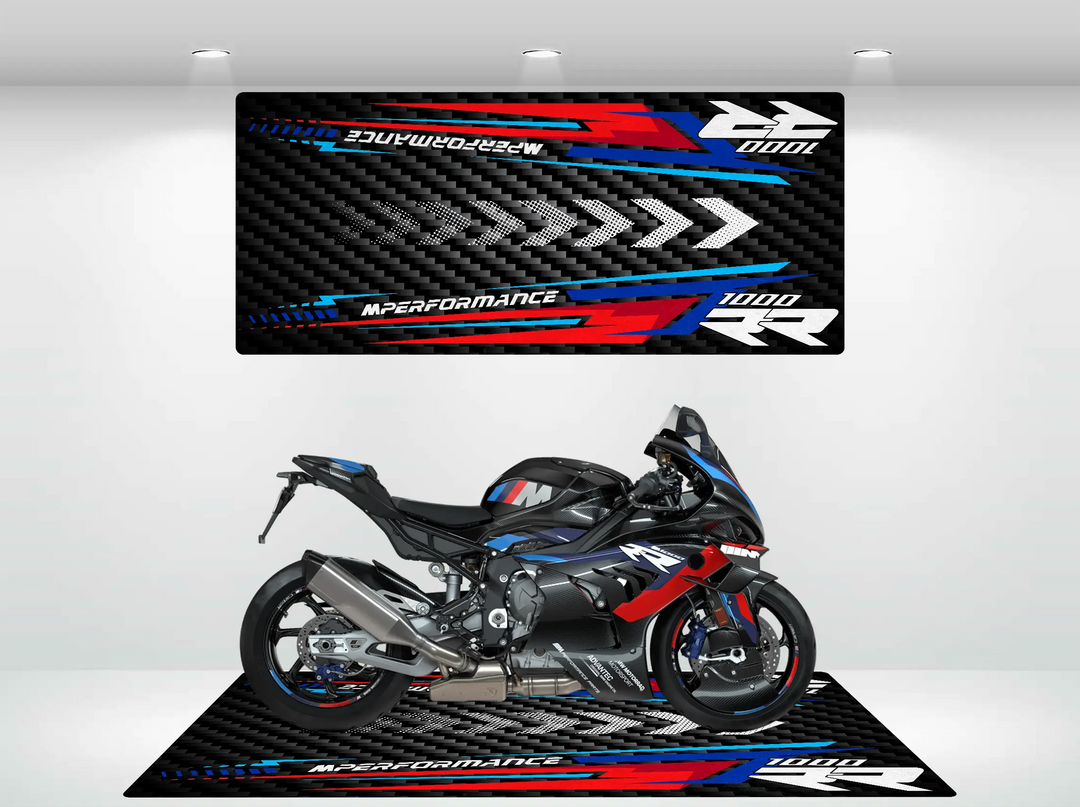 A black and blue sport motorcycle rests on the Motorcycle Pit Mat for the M1000RR, featuring matching colors and 1000 RR M PERFORMANCE text. The backdrop mirrors this with bold red, blue, and gray accents and stylized arrows for a dynamic display.