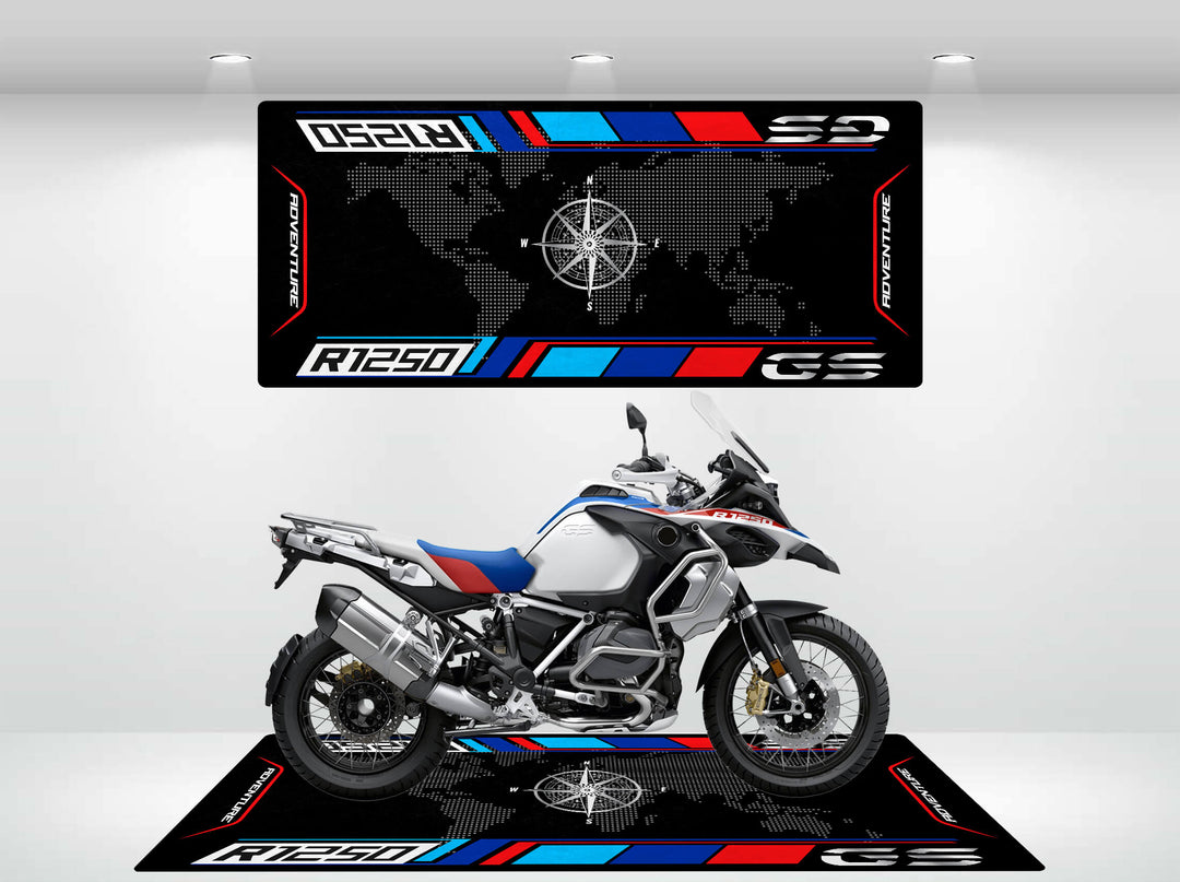 A motorcycle rests on a Motorcycle Mat for R1250 GS (Special Design) in a showroom, featuring a world map and R1250 GS Adventure text. The bike exhibits a sleek, sporty design with red, blue, and silver accents. Brand: Motorcycle Pit Mat.