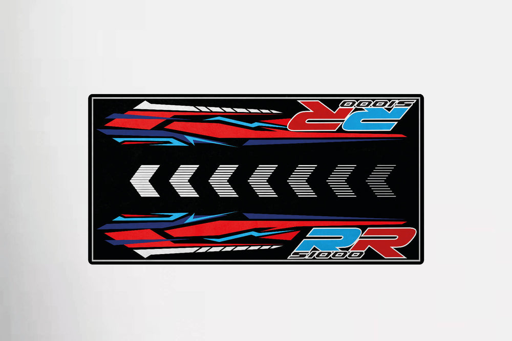 A bestselling Motorcycle Pit Mat mimics a rectangular decal design, showcasing bold red, blue, and white graphics with diagonal arrows centered around the letters RR and 1000, reflecting a dynamic and speed-driven theme for the S1000RR.