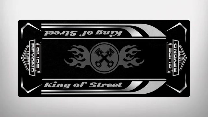 The Motorcycle Pit Mat in black and gray showcases two crossed wrenches with flame motifs at its center, surrounded by King of Street and GLIDE BEYOND LIMITS text. Decorative stripes and shapes adorn the edges.