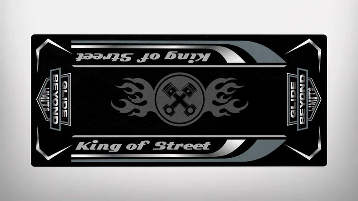 The King of Street - Glide Beyond Limits motorcycle mat by Motorcycle Pit Mat features a black and gray design with King of Street text, a flaming wrenches emblem, and decorative stripes, reflecting the bold style reminiscent of skateboard grip tape in a symmetrical layout.