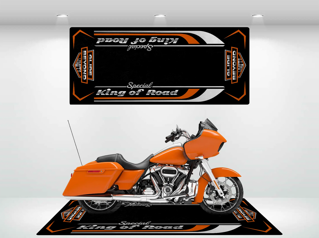 An orange Harley Davidson motorcycle sits on a black Motorcycle Mat for Road Glide special by Motorcycle Pit Mat. A matching garage mat with striking orange and white accents adorns the wall above.