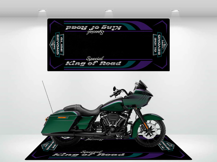 A green motorcycle with black accents is parked on a rectangular Motorcycle Pit Mat. The mat and backdrop display the text Road Glide Special amid decorative purple and black patterns. The brightly lit indoor setting echoes a Harley Davidson showroom ambiance.