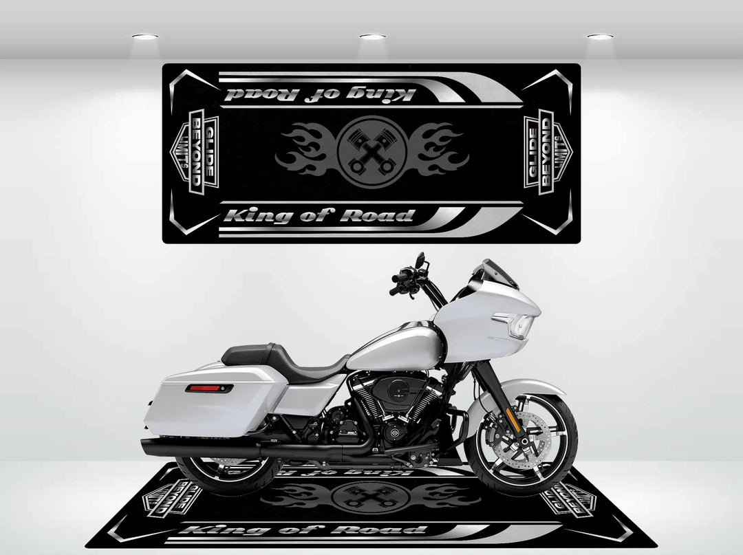 A sleek white Harley Davidson motorcycle sits on a durable black Motorcycle Pit Mat, featuring the Road Glide text with flame designs. A matching banner above on a white backdrop highlights its design under spotlights.