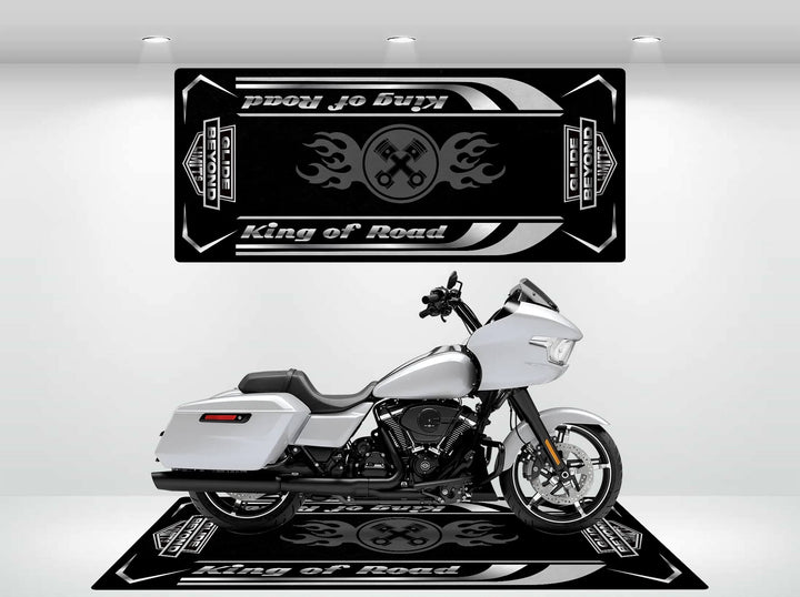 A sleek white Harley Davidson motorcycle sits on a durable black Motorcycle Pit Mat, featuring the Road Glide text with flame designs. A matching banner above on a white backdrop highlights its design under spotlights.