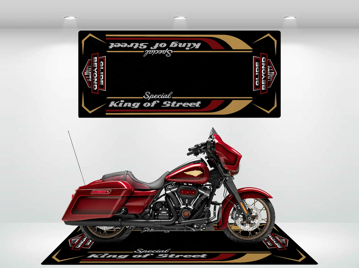 A red Harley Davidson rests on a durable custom black and gold Motorcycle Pit Mat, elegantly inscribed with Street Glide Special, enhancing its regal presence in a well-lit room.