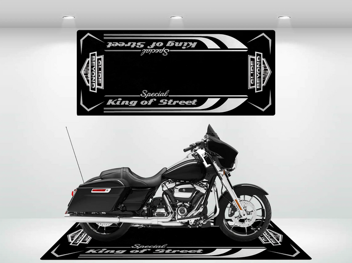 A black Harley Davidson with chrome details rests indoors on a durable Motorcycle Pit Mat, labeled Street Glide Special. The rooms white walls and three ceiling lights illuminate the scene.