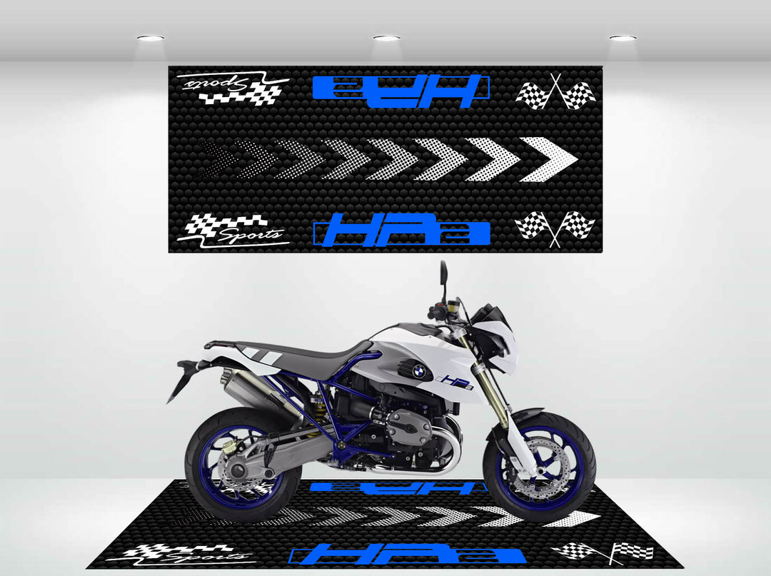 In a modern showroom, a sleek motorcycle sits on the Motorcycle Pit Mats HP2 Sport mat. The scene, featuring arrows and racing motifs in black, white, and blue on the backdrop, glows vividly under bright lights.