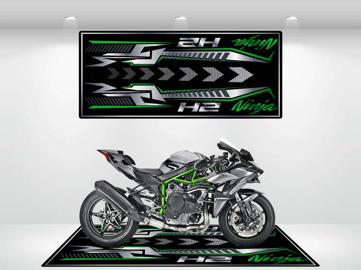 A sleek silver and green motorcycle is showcased under bright lights on a Motorcycle Pit Mat, designed specifically for the Kawasaki H2. Matching patterns with Ninja and H2 in green and white adorn the floor and walls.