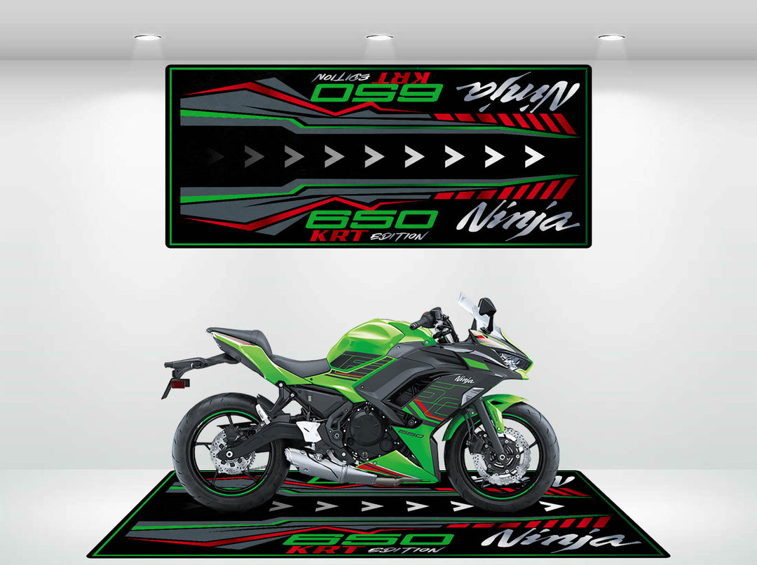 A Kawasaki Ninja 650 KRT Edition motorcycle sits on a matching Motorcycle Pit Mat in the showroom, highlighted by vibrant backdrop graphics with 650 KRT Edition and Ninja text in bold red and white. The display is enhanced by white walls and bright overhead lighting.