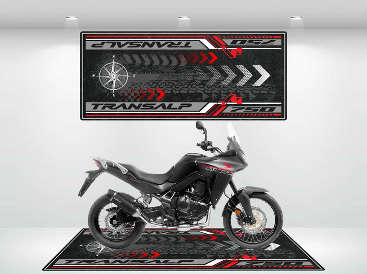 A black adventure motorcycle sits in a showroom, enhanced by a Motorcycle Pit Mat for the Honda Transalp 750. This custom garage mat features red, black, and white graphics with Transalp and tire tracks, all elegantly showcased in a modern setting.