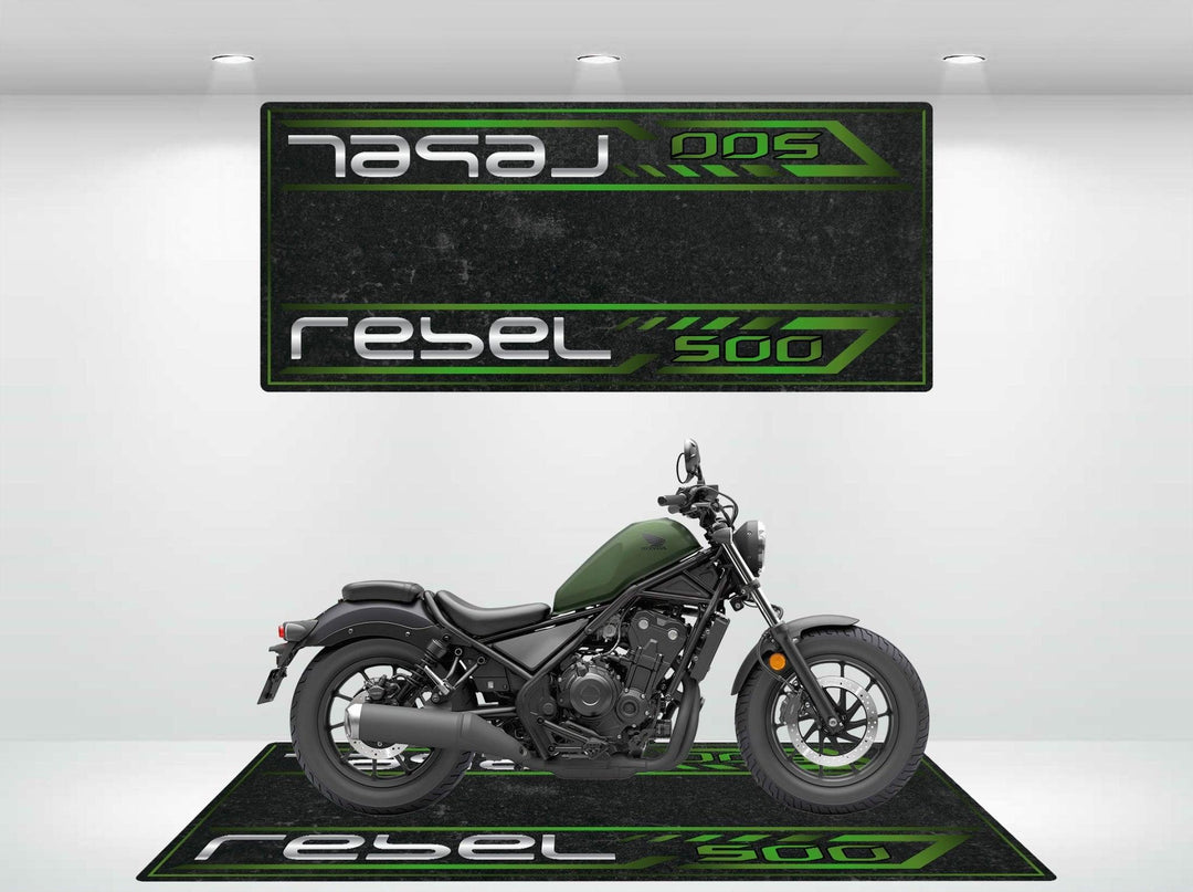 A black and green Honda Rebel 500 motorcycle is showcased in a showroom, enhanced by matching wall and floor designs featuring Rebel 500 in bold text. A sleek Motorcycle Pit Mat for the Honda Rebel 500 completes the setup, where style meets functionality.