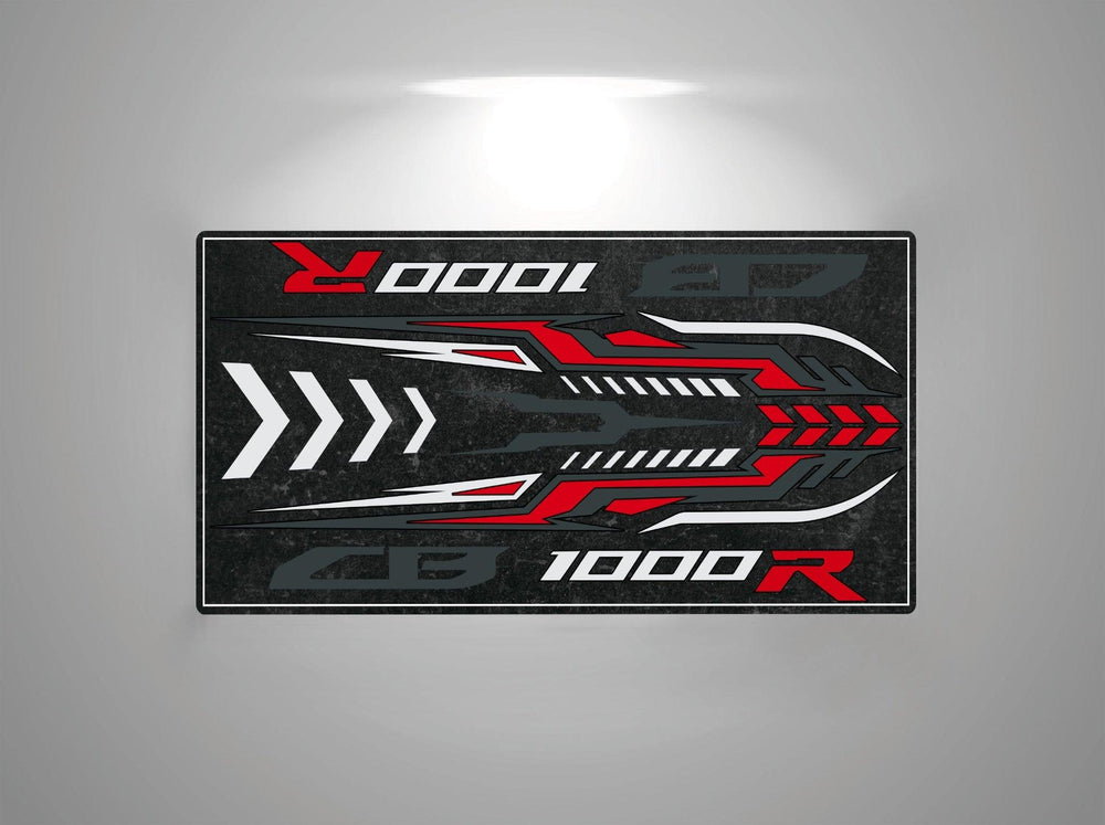 The Motorcycle Pit Mat for Honda CB1000R showcases a sleek, futuristic rectangular design with bold red, white, and gray geometric patterns. 1000R stands out prominently in red and white on a dark backdrop, enhanced by dynamic arrow motifs.