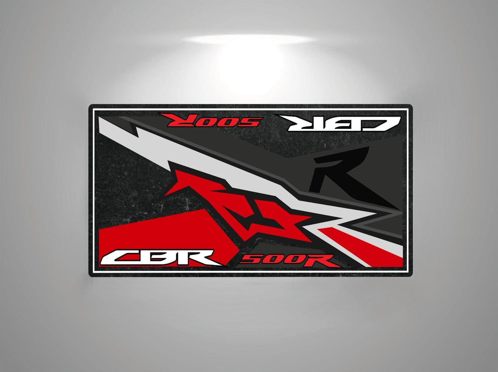 A rectangular graphic for the Motorcycle Pit Mat showcases Motorcycle Mat for Honda CBR500R in bold red and white letters on a dark background, featuring abstract red, black, and gray elements reminiscent of a sleek motorcycle floor mat.