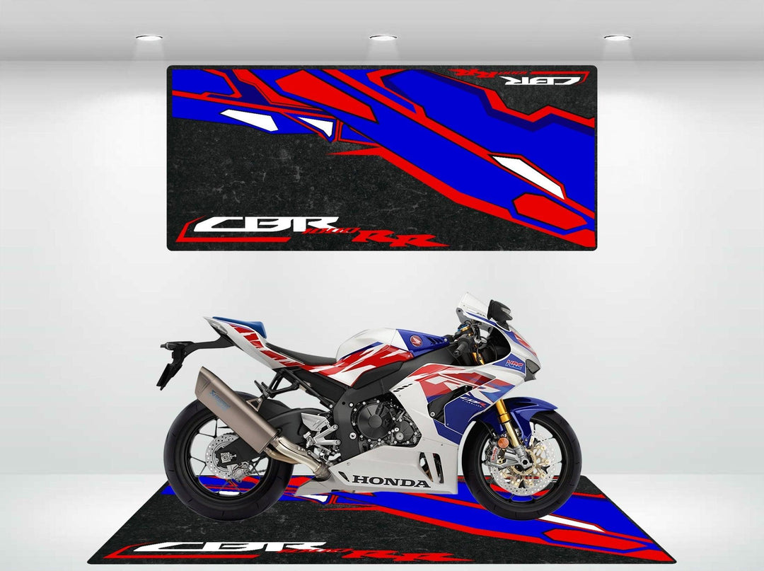 A Honda CBR1000RR with a sleek white, blue, and red design rests on a Motorcycle Pit Mat. Above it, a large banner vividly highlights the bikes speed and style with a stylized graphic.