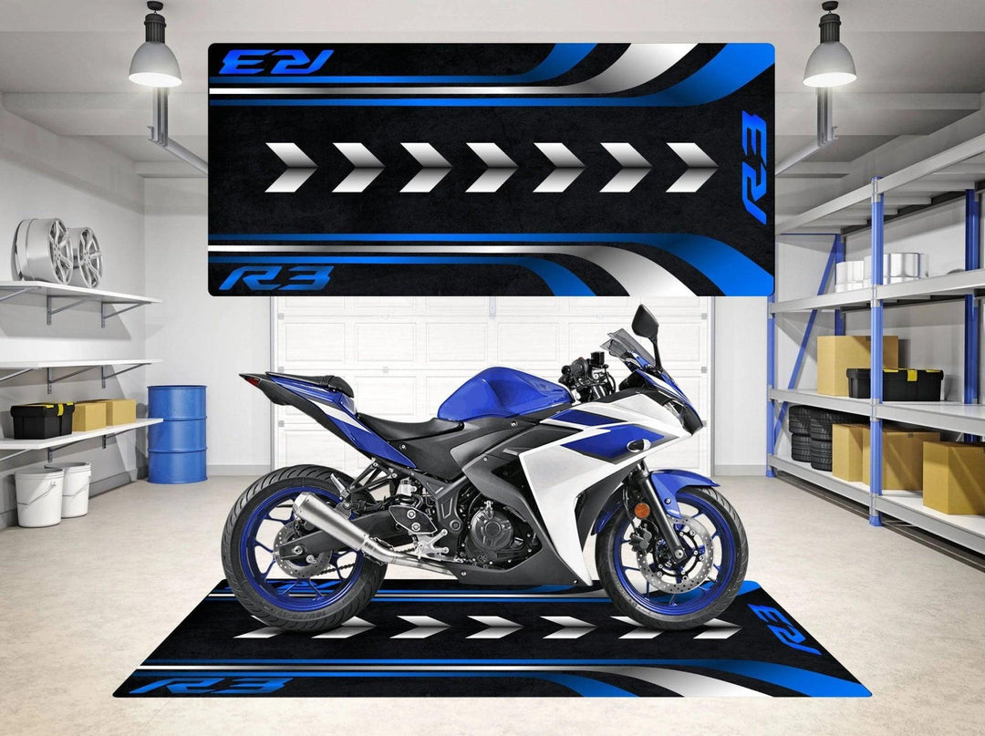 A Yamaha R3 sports motorcycle in blue and white is displayed on a showroom floor, complemented by a Motorcycle Pit Mat for Yamaha R3 with blue and black designs. Shelves with storage boxes surround the space, with car rims visible in the corner.