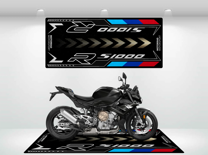 A sleek black motorcycle is showcased on a Motorcycle Pit Mat, specifically the Motorcycle Mat for S1000R. The mat features racing themes in black, silver, blue, and red. In the background is a R 1000 S design. Excellent lighting accentuates the bikes details.