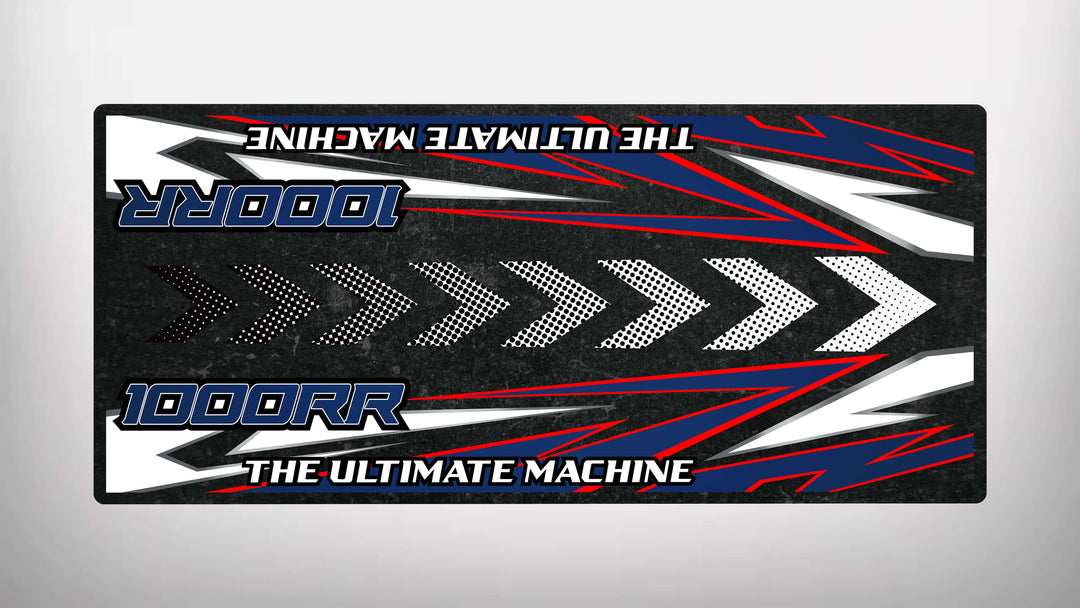 Rectangular decal design with 1000RR and The Ultimate Machine in bold. It has dynamic red, white, and blue stripes and arrows on a dark background reminiscent of a Motorcycle Pit Mat for S1000RR.