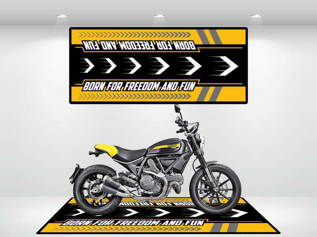 A yellow and black motorcycle displays confidently on the Motorcycle Mat for Scrambler by Motorcycle Pit Mat, featuring bold stripes and the phrase Born for Freedom and Fun, evoking a sense of adventure and speed.