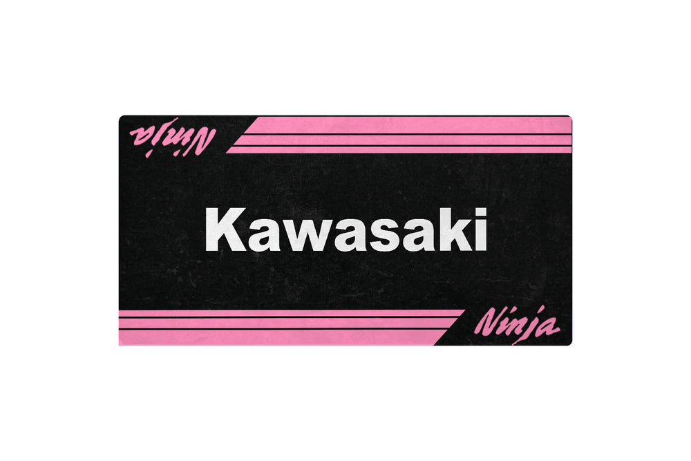 The Motorcycle Pit Mat X SMALL VROOM Kawasaki Ninja Mat features a black background with pink stripes, the word Kawasaki in white at its center, and Ninja in pink cursive at the corners—ideal for enhancing any motorcycle enthusiasts garage.