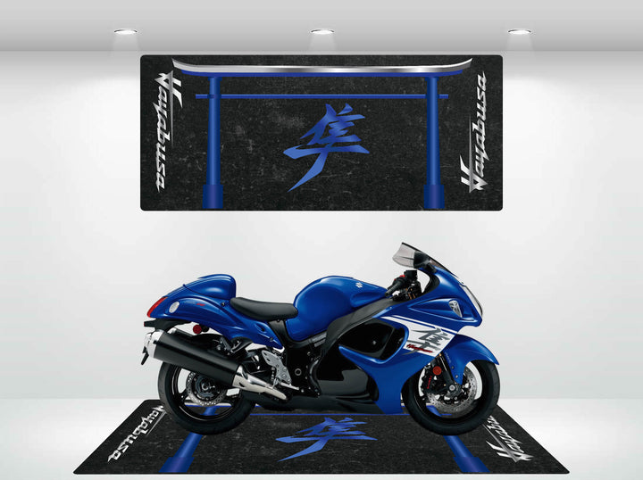 A blue motorcycle is showcased on a sleek Motorcycle Pit Mat for Suzuki Hayabusa with blue and white designs, while a matching wall banner above is lit by spotlights.