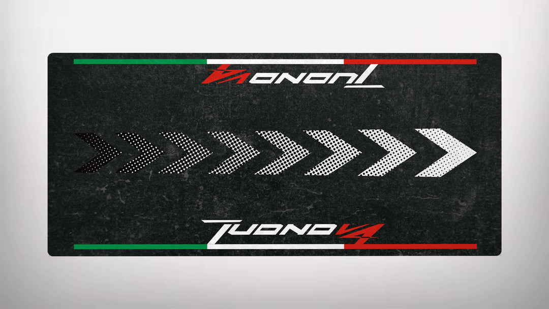 The Motorcycle Pit Mat, a rectangular motorcycle mat for the Tuono V4 Italian, has a black background featuring Tuono in white and red at the top, Tuono V4 at the bottom, chevrons pointing right in black and white in the center, and red and green stripes on top and bottom.