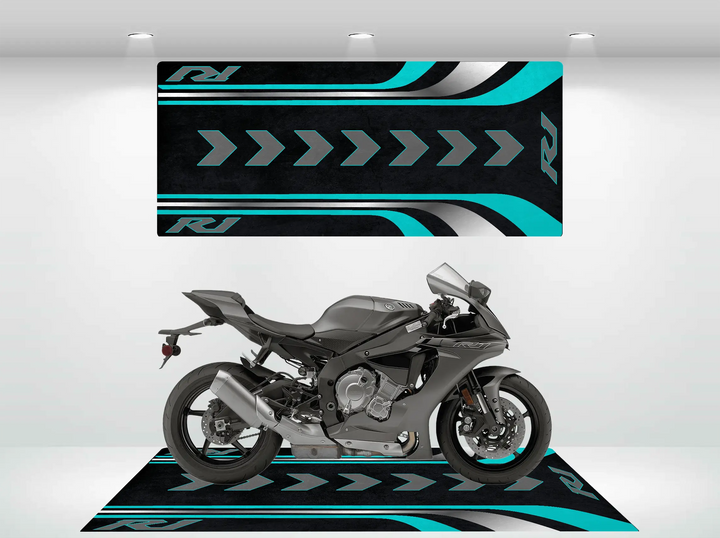 A sleek black motorcycle is displayed in a modern showroom, perfectly complemented by the Motorcycle Pit Mat for Yamaha R1 in black, teal, and white. Its arrow patterns and stylized RJ logos seamlessly integrate with the striking wall design.