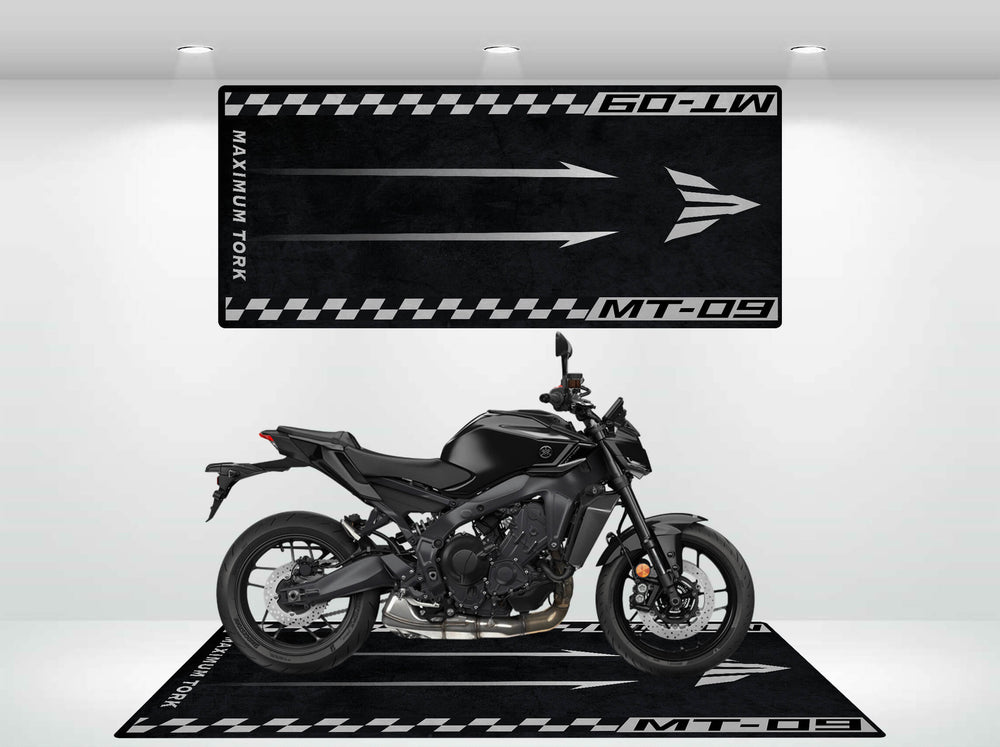 A sleek black motorcycle in a showroom features decorative black and white banners with MT-09 arrows, emphasizing speed and modern design. Beneath it is the elegant Motorcycle Pit Mats Motorcycle Mat for Yamaha MT-09, enhancing the display.