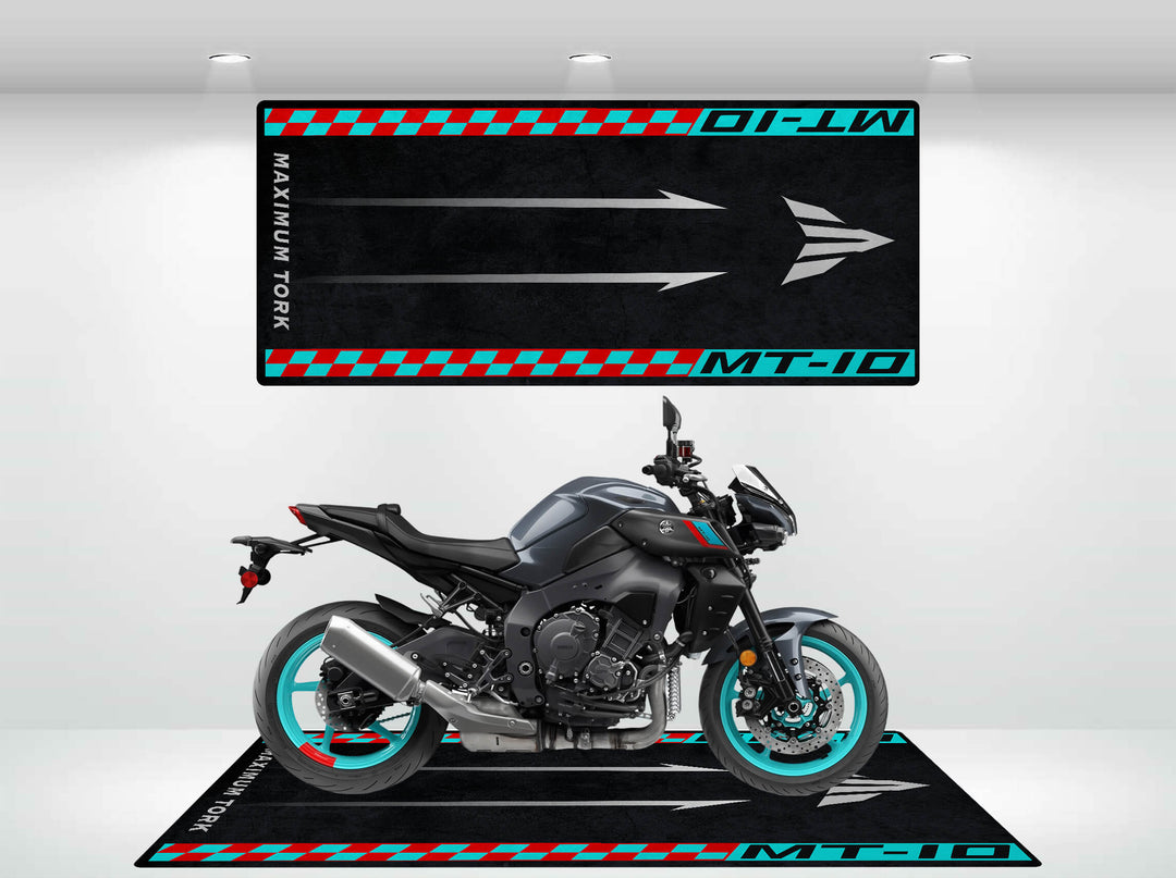 A black motorcycle with blue rims stands on a checkered Motorcycle Mat for Yamaha MT-10 by Motorcycle Pit Mat. A matching arrow graphic banner hangs above, set against a well-lit white background, creating a striking display.