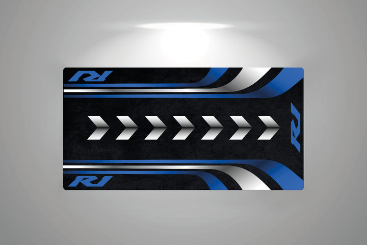 The Motorcycle Pit Mat for the Yamaha R1 is a rectangular floor mat with a sleek design of blue and silver stripes, white arrows on black, and stylized RJ initials in the corners for added sophistication.