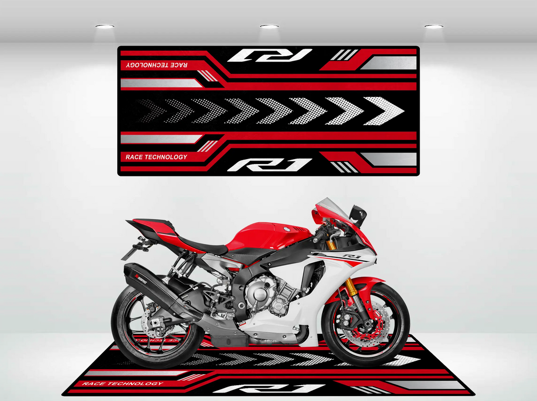 A red and white sport motorcycle rests on a Motorcycle Pit Mats Yamaha R1 2025 Design, showcasing bold geometric patterns in red, black, and white. Above it, wall art mirrors these colors with arrows and text saying Race Technology and R1.