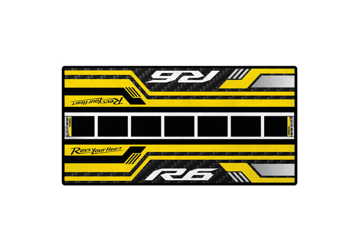 The Motorcycle Pit Mat for the Yamaha R6 60th Anniversary is a rectangular mat with a black and yellow carbon fiber design, featuring bold yellow stripes, R6 and Revs Your Heart text in white and yellow, white squares, ideal as a motorcycle garage mat.