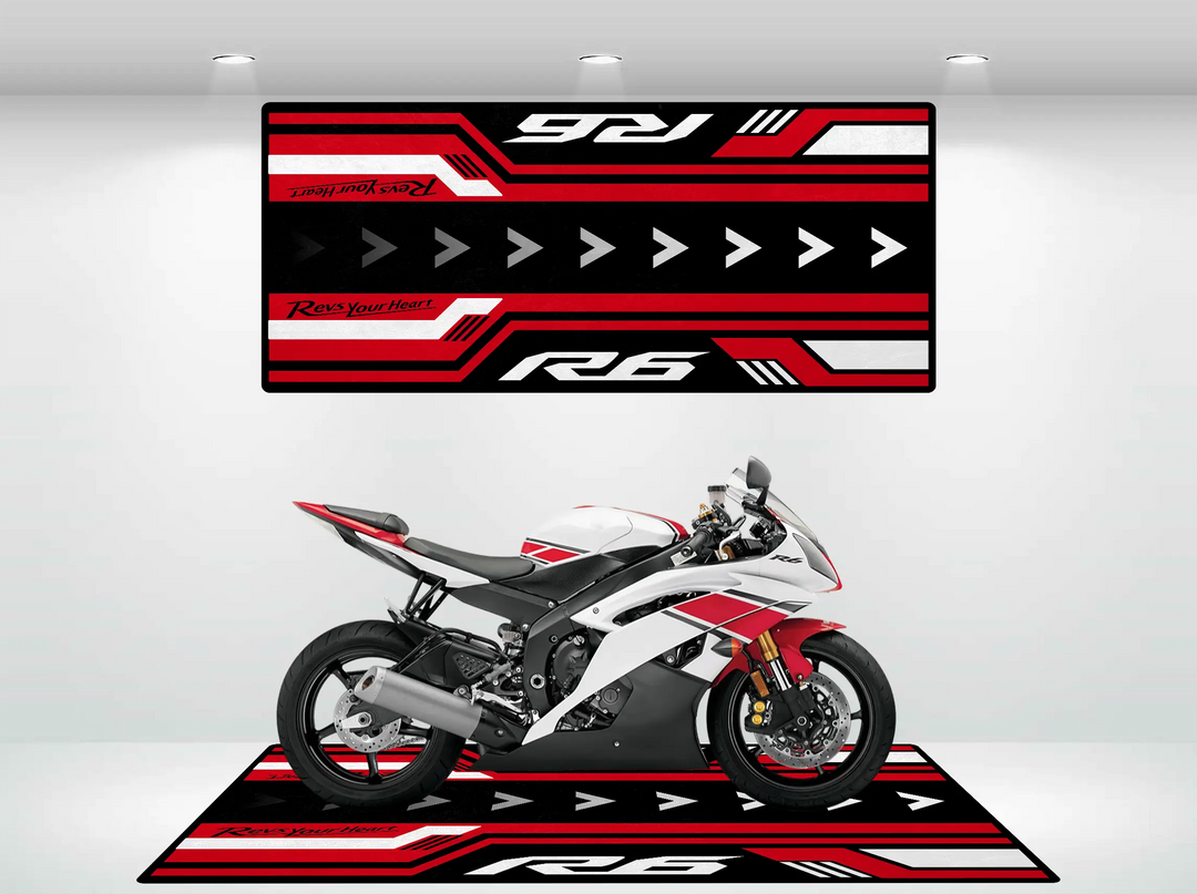 A white and red motorcycle sits on the Yamaha R6 Vintage Motorcycle Mat by Motorcycle Pit Mat, adorned with bold graphics and diagonal lines. Above, a wall hanging complements the look with striking R6 text.