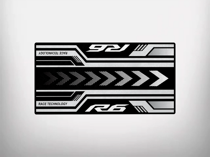 The Motorcycle Pit Mat for Yamaha R6 features a black rectangular design with bold white arrows pointing right and horizontal lines, enhanced by R6 and Race Technology text. The light gray background offers a clean, modern look, perfect for your garage floor.