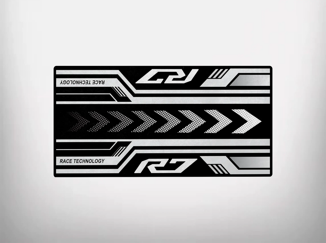 The Motorcycle Pit Mat for Yamaha R7 showcases arrows and geometric shapes on a rectangle, ideal for a motorcycle garage. It features the text Race Technology with bold R and Z, using black, white, and gray for a sleek design.