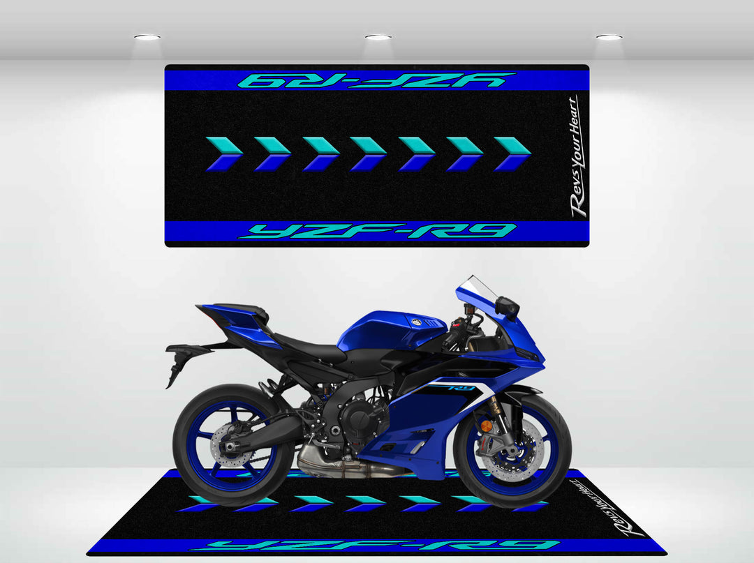 Displayed in the showroom is a blue Yamaha R9 sport motorcycle, surrounded by black and blue banners with geometric designs featuring YZF-R9 and Rev Your Heart. It sits centered on a matching Motorcycle Pit Mat for a sleek presentation.