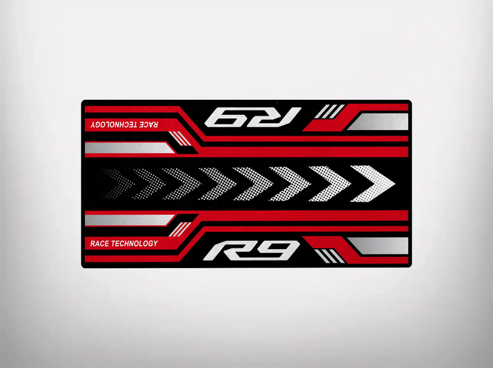 A rectangular graphic showcases a vibrant mix of red, black, and white geometric patterns with rightward arrows. Featuring stylized Race Technology and R9 text, this dynamic design by Motorcycle Pit Mat mirrors the sleek Yamaha R9 motorcycle mat, enhancing any garage or pit area.