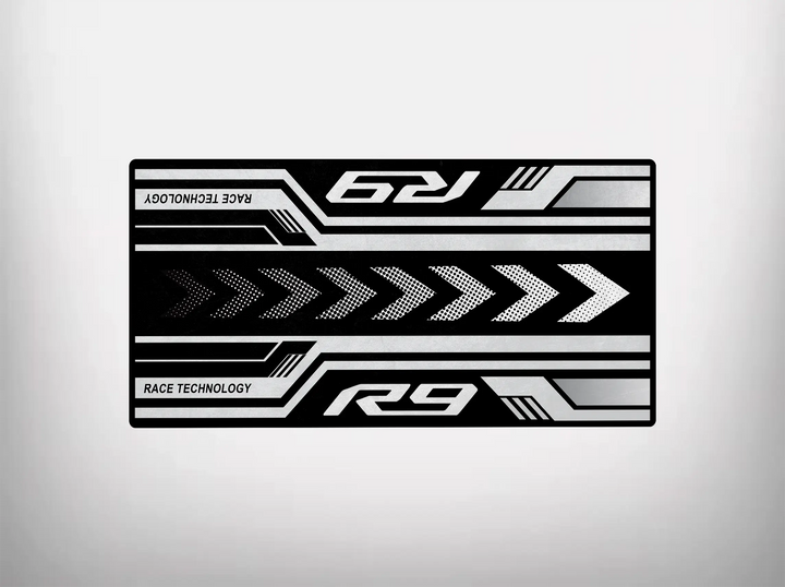 The black rectangular Motorcycle Mat for Yamaha R9 by Motorcycle Pit Mat features white and gray geometric patterns, arrows, and lines. With R9 printed twice alongside Race Technology, it offers a dynamic racing aesthetic perfect for any Yamaha motorcycle mat or garage floor.