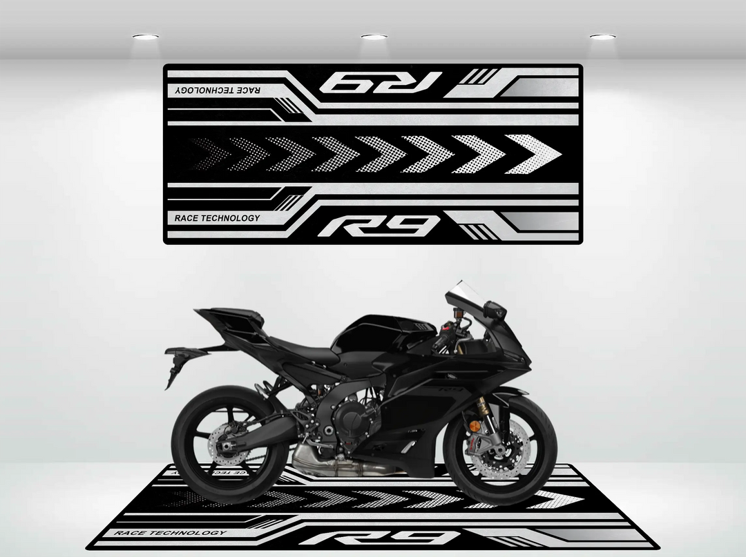 A sleek black motorcycle sits on a Motorcycle Pit Mat designed for the Yamaha R9, featuring geometric patterns in a showroom. Above, a banner showcases bold graphics with arrows and the phrase Race Technology highlighting the R9.